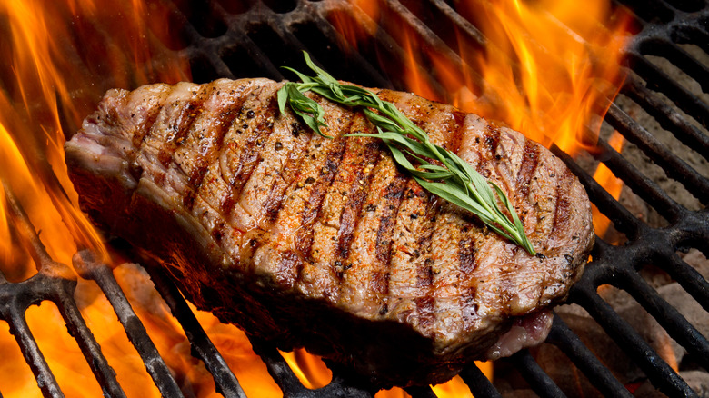 A Tomahawk steak on a grill with herbs