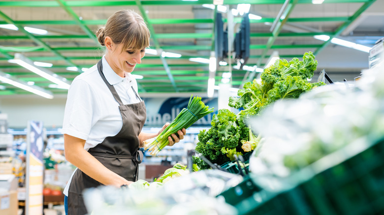 Grocery store employee restocks produce