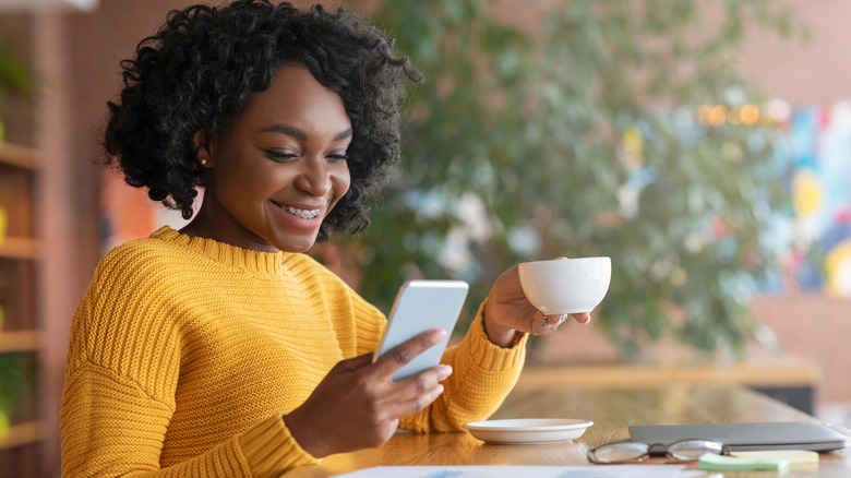 Woman drinking coffee and using her phone