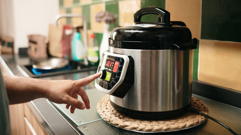 Hand adjusting slow cooker controls