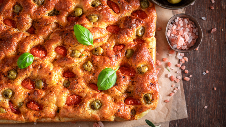 close-up of focaccia with olives, tomatoes, and basil