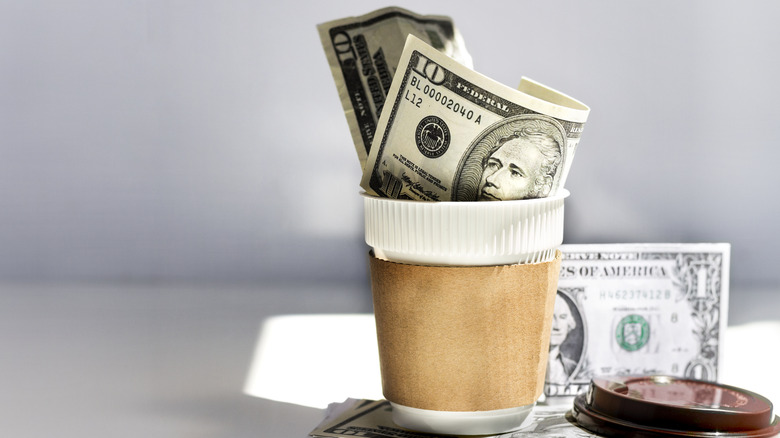 Money in coffee cup with paper sleeve