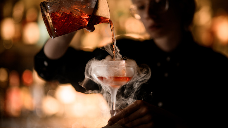 Bartender pouring a smoky bourbon cocktail