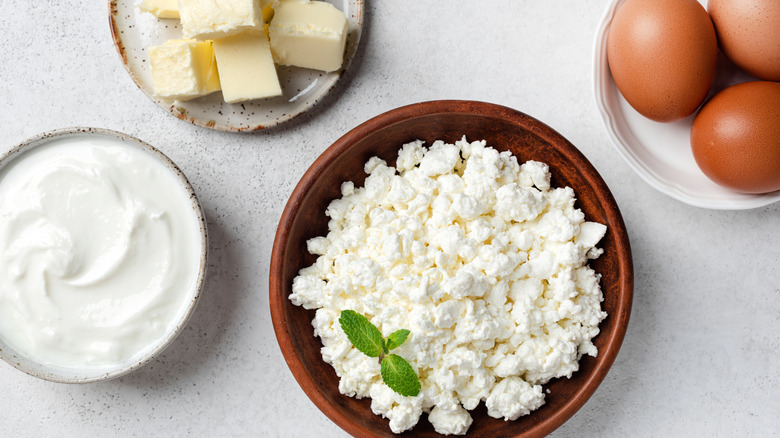 bowl of cottage cheese with bowl of yogurt, a few whole eggs, and pats of butter