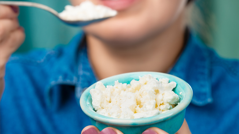 person spooning cottage cheese out of a small bowl