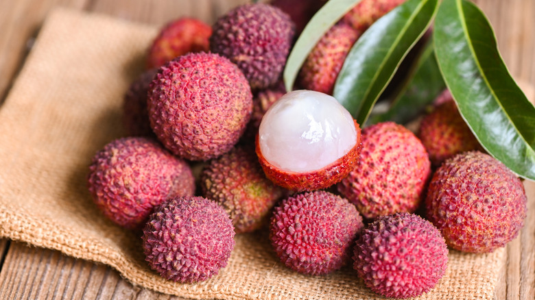 Fresh, ripe lychees on a cloth, one shelled
