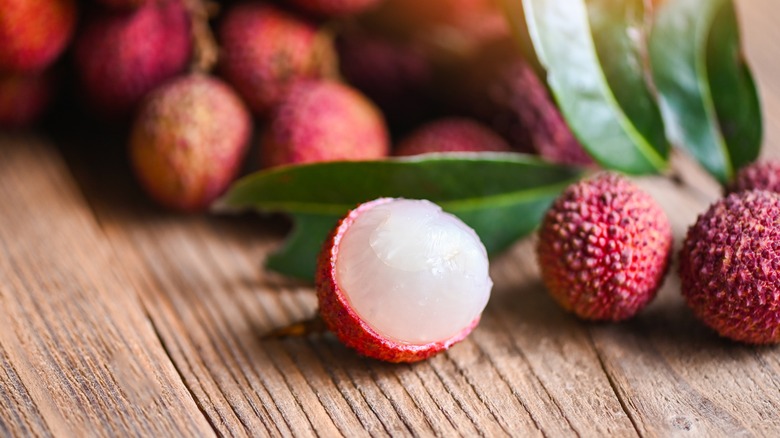 Close-up shot of a lychee, one shelled, on wood table
