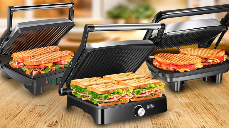 Three open panini presses filled with sandwiches