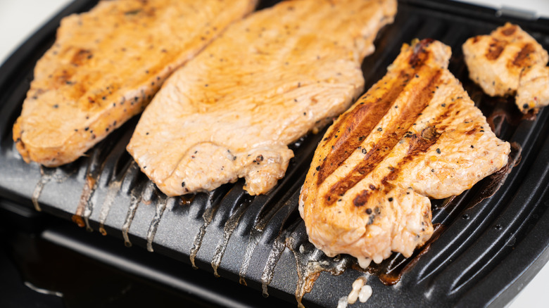 Chicken fillets grilling on an open panini press