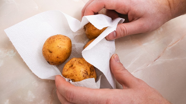 Hands holding potatoes in a paper towel