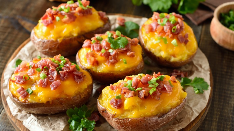 loaded baked potatoes on a wood board