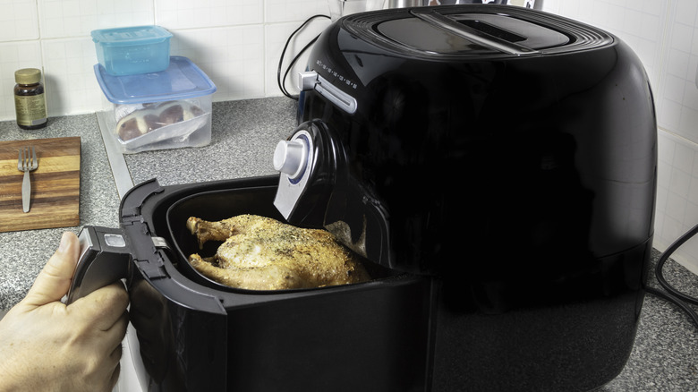 person uses air fryer to cook chicken