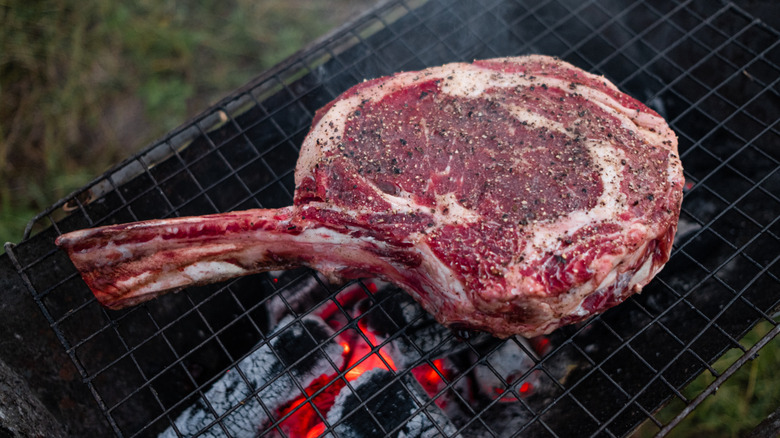 Seasoned Tomahawk steak cooking on a grill