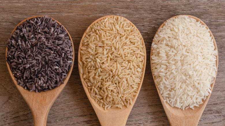 3 types of uncooked rice on large wooden spoons