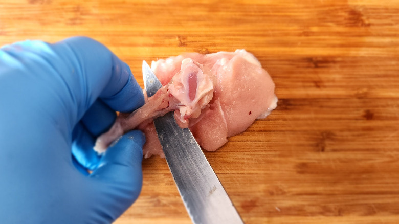 Gloved hands cutting the bone free from a chicken wing's "drumette"
