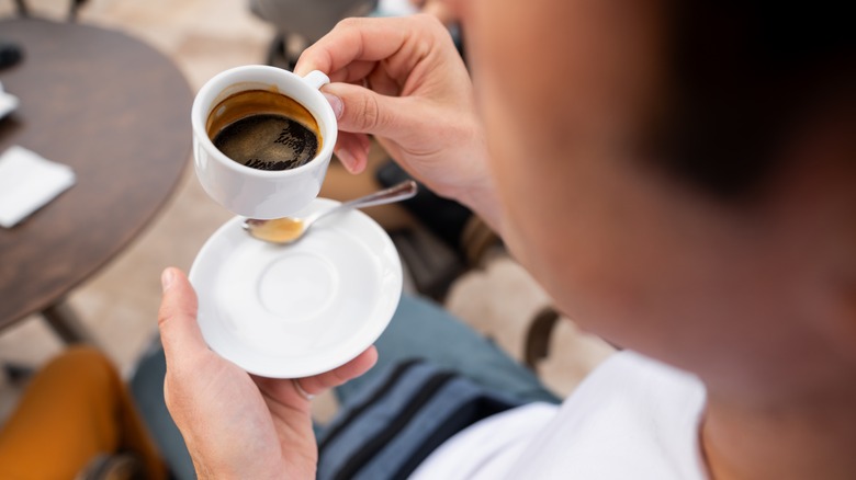 Person holding espresso shot saucer