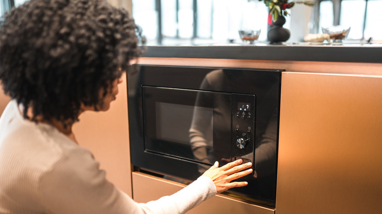 woman pressing microwave button