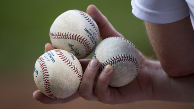 baseball player holding three baseballs