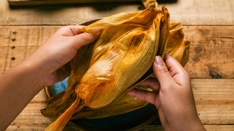 hand opening a tamale 