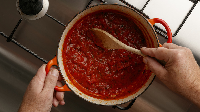 stirring tomato sauce wooden spoon