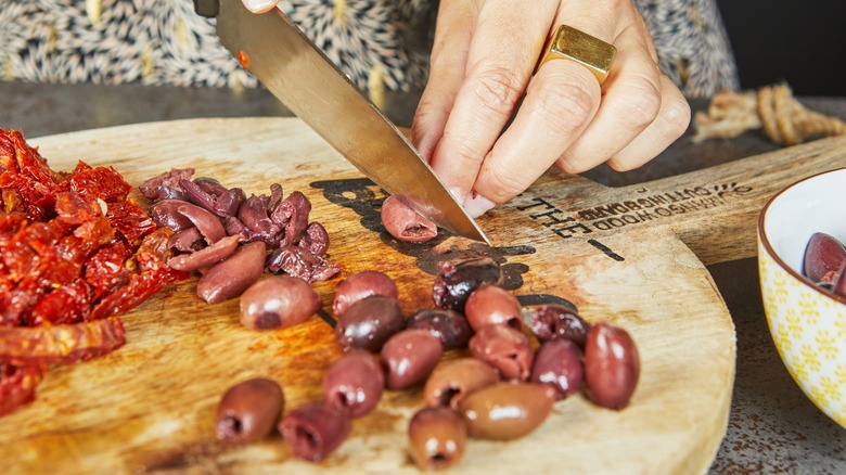 Hand cutting up olives and sun-dried tomatoes