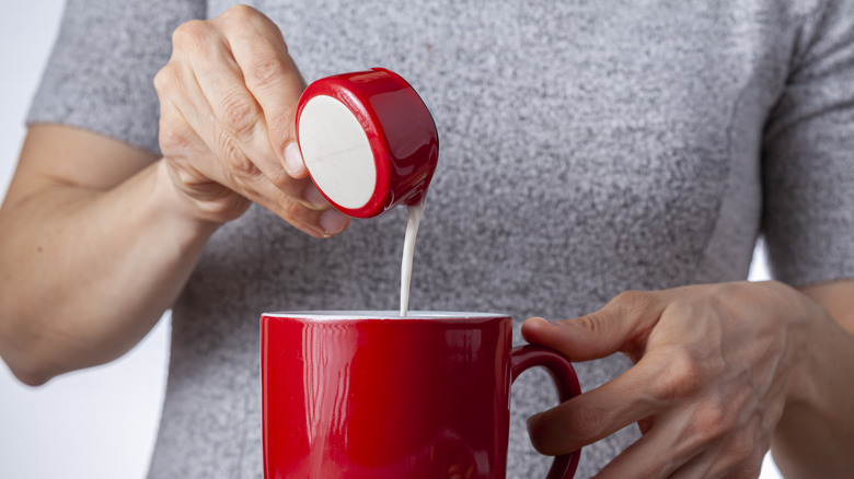 pouring coffee creamer into cup