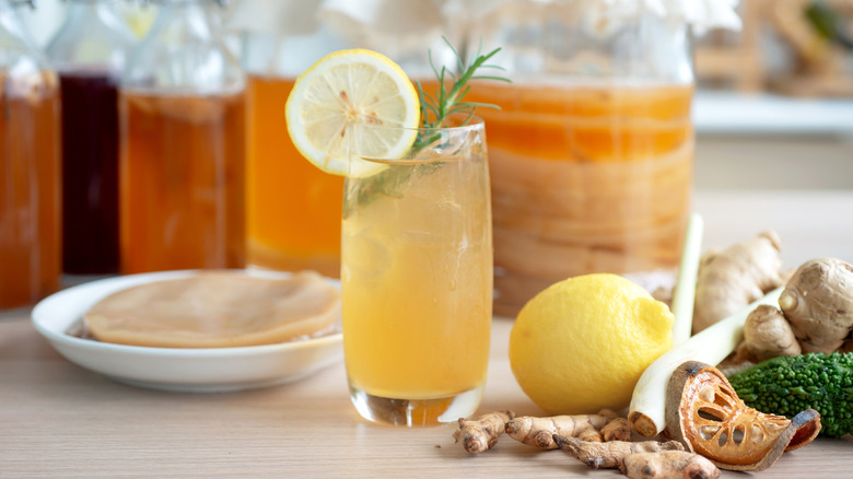 Different colored bottles of homemade kombucha and a freshly poured and garnished glass