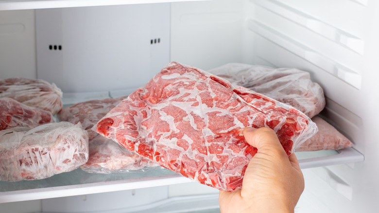 Hand pulling meat from freezer