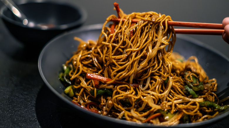 chop sticks pulling a bite of stir fry noodles