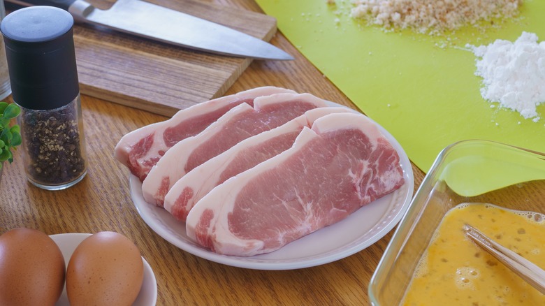 Raw pork chops and breading ingredients