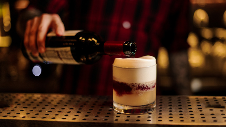 bartender pouring red wine into cocktail