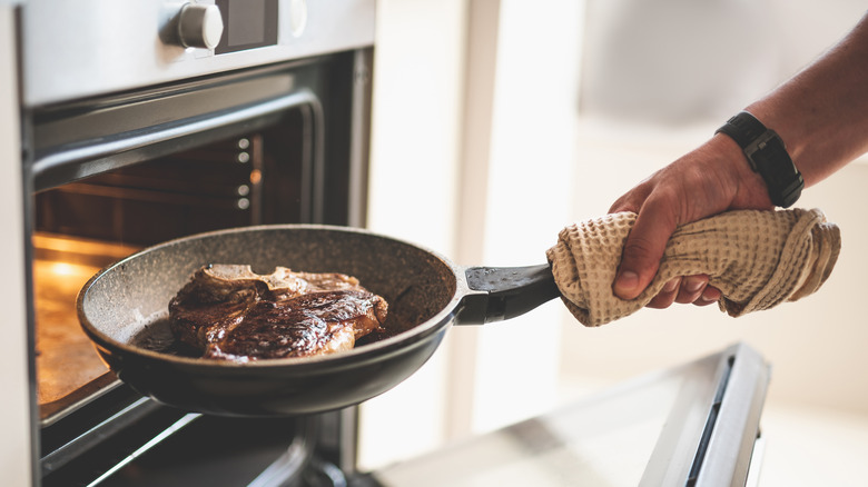 male holding steak near oven