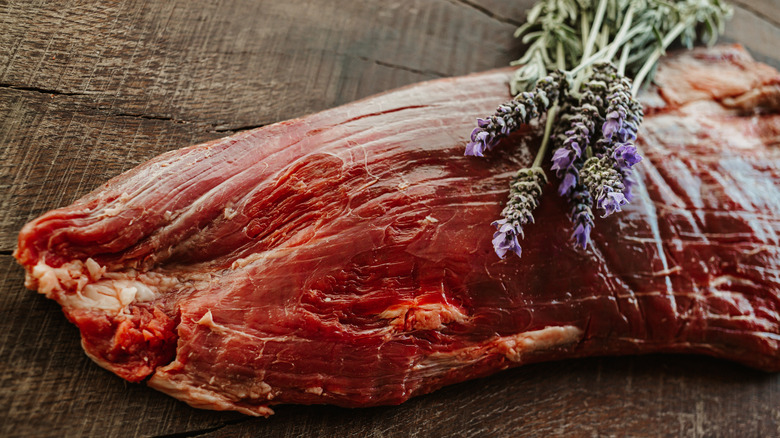 raw flank steak on wood table