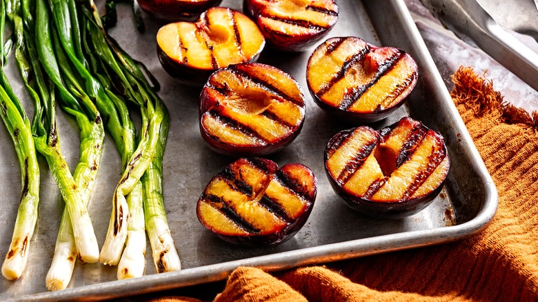 Pan of grilled spring onions and peaches