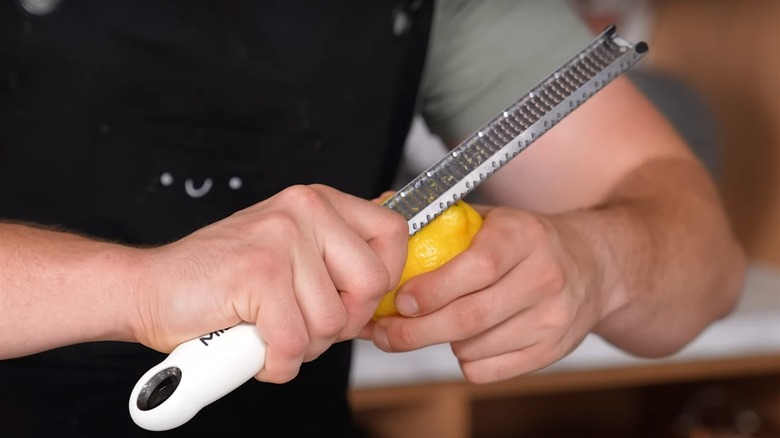 holding a microplane over a lemon