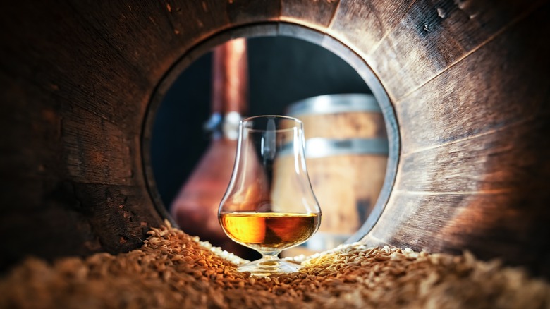 glass of whiskey in an oak barrel