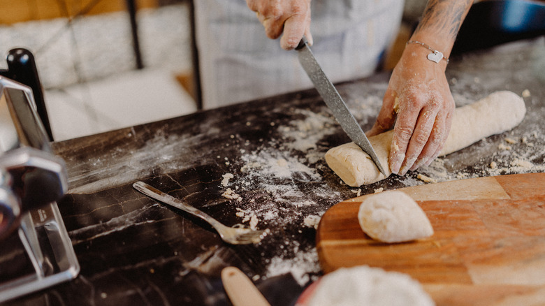 person cutting fresh pasta dough