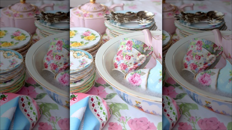 Handwashing vintage teacups in a bowl of water