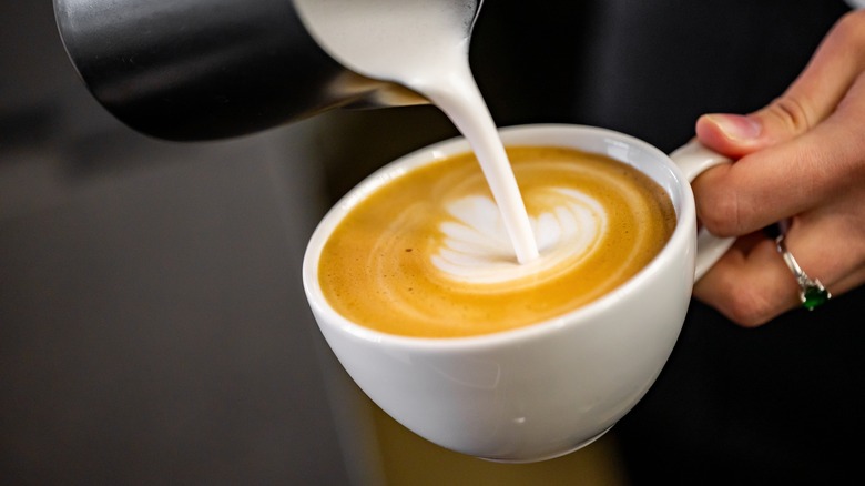 Pouring steamed milk in coffee