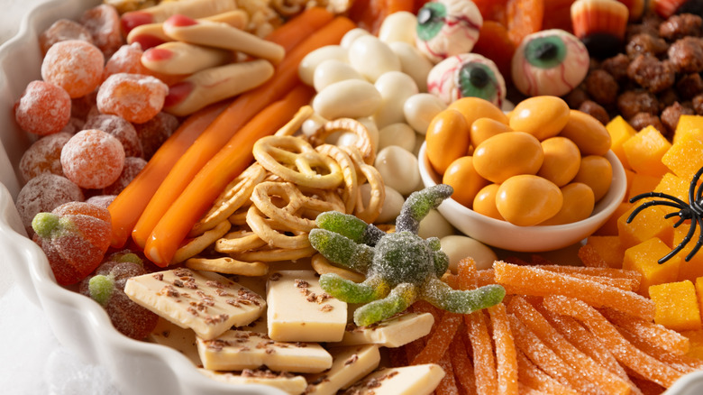 Halloween charcuterie bowl with candy, pretzels, and spooky decorations