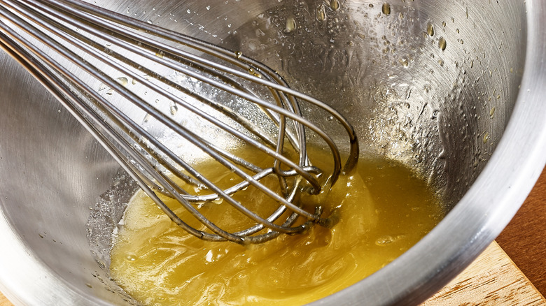 close up of whisk in yellow liquid