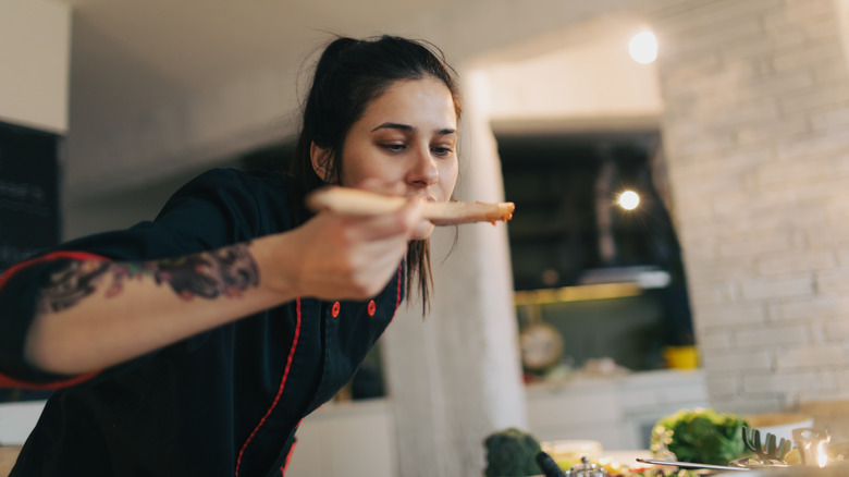 chef tasting sauce with spoon