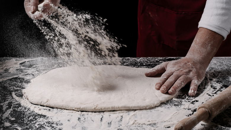 rolled out pizza dough on a floured surface