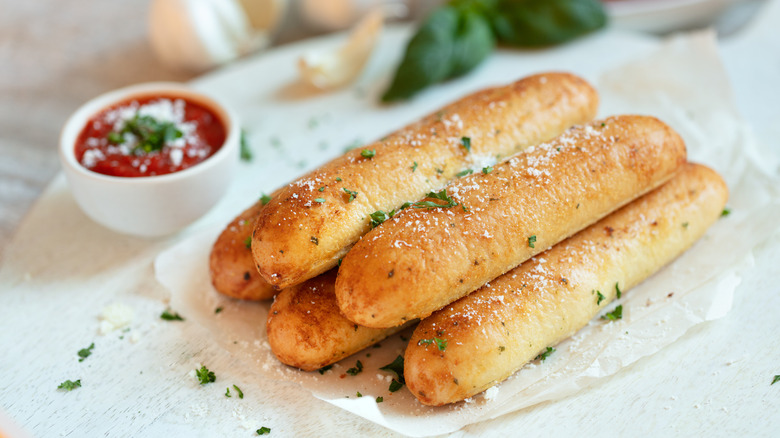 pile of garlic breadsticks with side of marinara dipping sauce