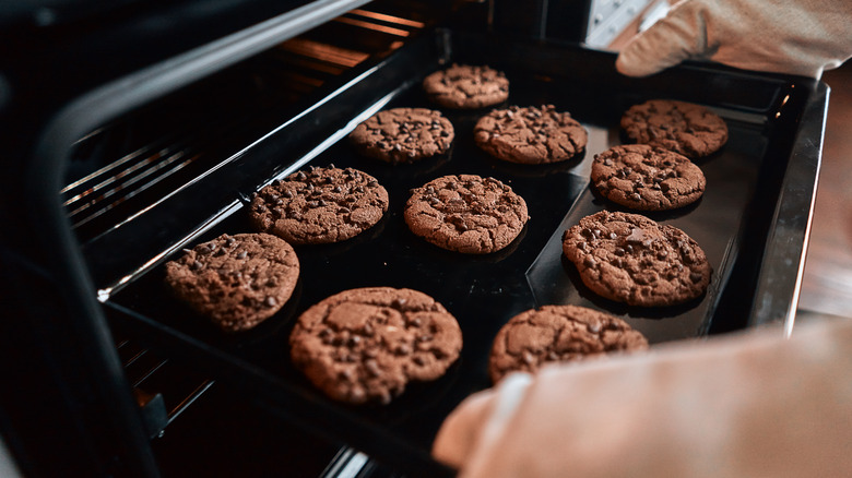 hands putting cookies in oven