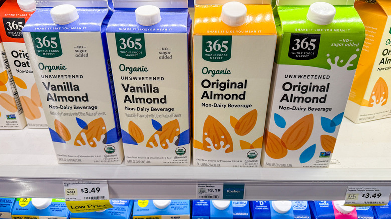 Several half-gallon cartons of almond milk sit on a shelf.