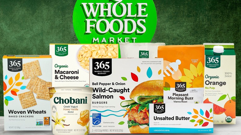 A group of packaged foods from Whole Foods sits in front of the market's logo.