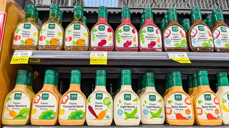 A row of 365 brand salad dressing is displayed on grocery store shelves.