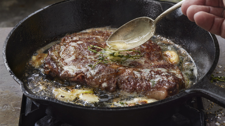 basting steak with fat in a skillet