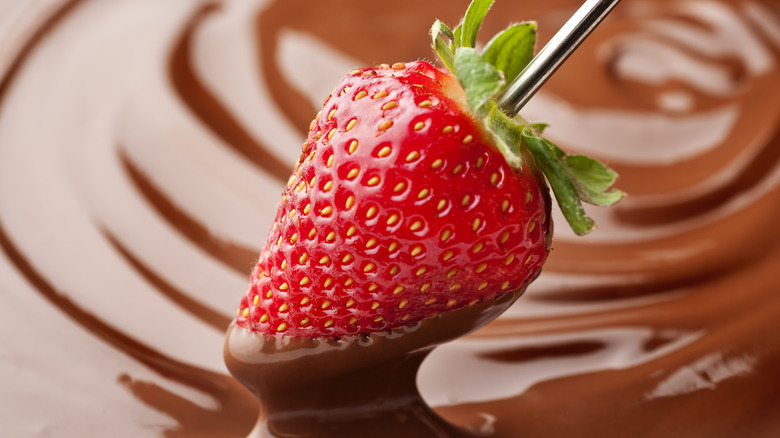 Strawberry being dipped in melted chocolate 